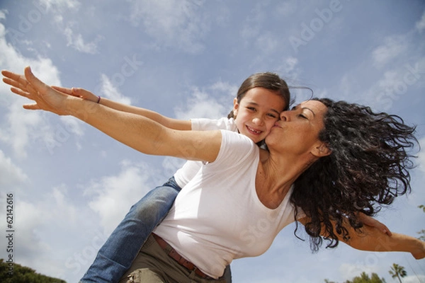 Obraz Madre besando a su hija mientras juegan a volar