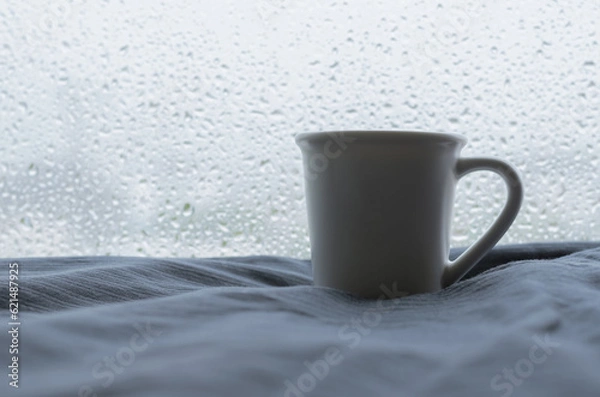Fototapeta A cup of Espresso coffee shot puts on bed with rain drop on window in raining day. Stay home concept.