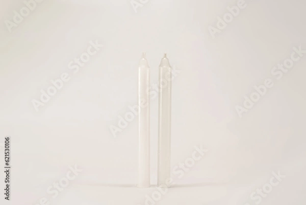 Fototapeta Two white wax unlit candle without fire isolated on white background with low light shadow