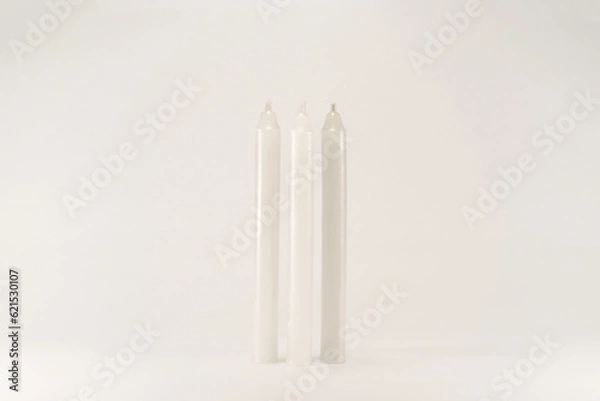 Fototapeta Three white wax unlit candle without fire isolated on white background with low light shadow