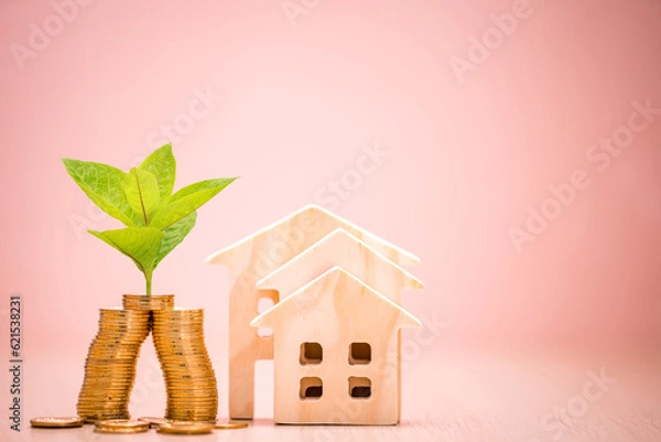Obraz Stack gold coin with plant growing value on the top and the stack wooden house on the pink background in the office, Business investment or loan for real estate concept.
