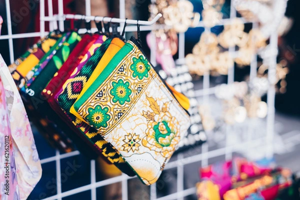 Fototapeta Closeup of multi-colored patterned purses on a rack of product display. Selective focus. 
