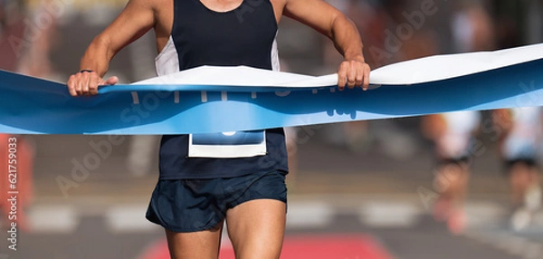 Fototapeta Man running towards the finish line, male runner win the race outdoor in the city. Passes finish line as a winner