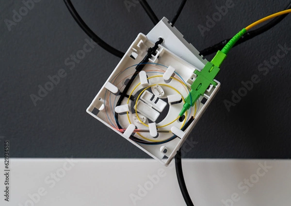 Fototapeta Installation of fiber optic cable in a box on the wall at home. High speed internet connection, new network equipment for a house.