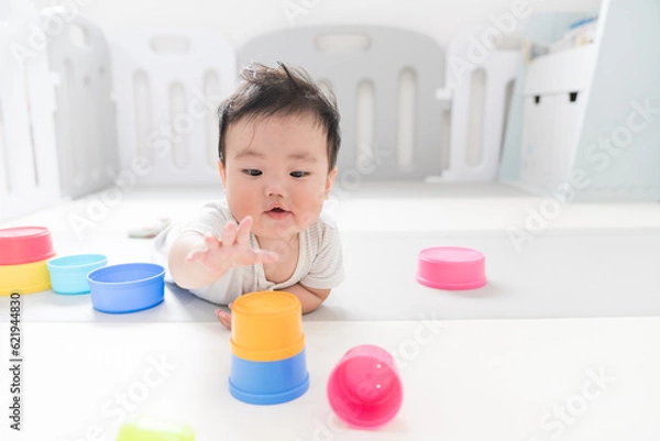 Fototapeta 自然光が入るリビングのプレイマットで知育おもちゃをつかんで遊ぶご機嫌な生後8か月の赤ちゃん