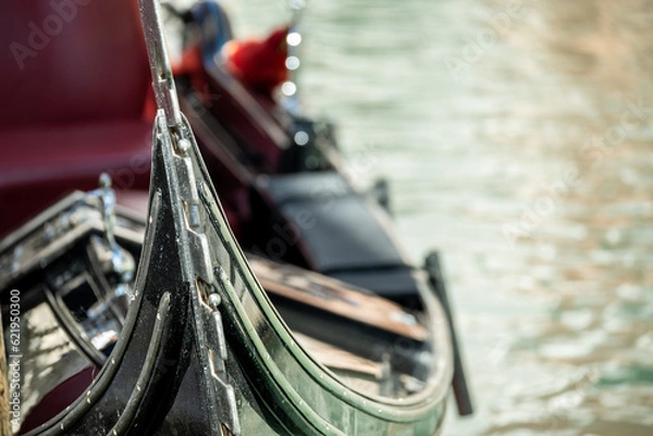 Fototapeta Fragment of a gondola, a Venetian boat on a blurred background of the canal water. Focus on the bow of the boat.