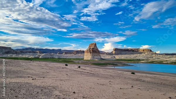 Fototapeta Panoramic view on solitary rock formations Lone Rock in Wahweap Bay in Lake Powell in Glen Canyon Recreation Area, Page, Utah, USA. Road trip to sand beach on wild campground in sunny summer. Vacay