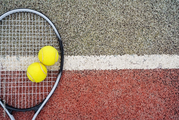 Fototapeta Closeup top view on yellow tennis balls and racket racquet lying on acrylic tennis hard court surface with empty blank copy space.