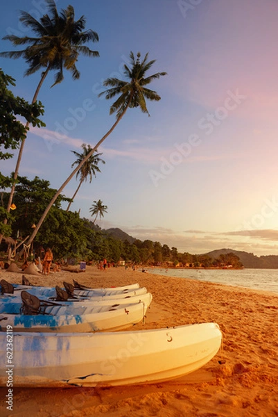 Fototapeta Summer seaside beach in evening There are kayaks and warm sunshine, perfect for a holiday getaway.		