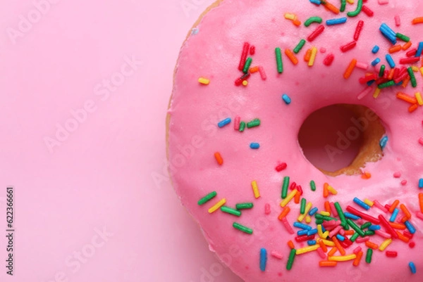 Fototapeta Tasty glazed donut decorated with sprinkles on pink background, closeup. Space for text