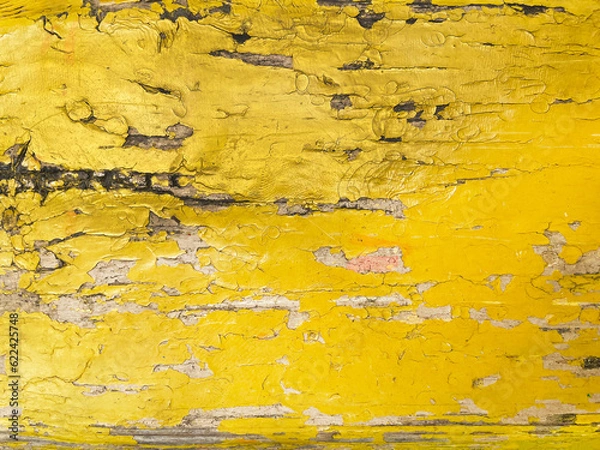 Fototapeta Old peeling wooden lath painted with yellow paint, close-up, top view. The surface of the lath is cracked, worn, with large and small cracks.