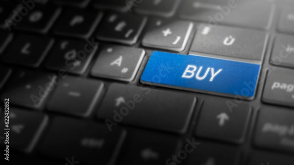 Fototapeta Buy key on laptop computer keyboard, blue button on the dark grey keybord of a modern laptop notebook, e-commerce concept for online purchasing and shopping, close-up