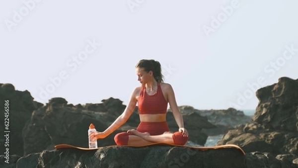 Obraz young woman is drinking water while practicing yoga in the lotus pose