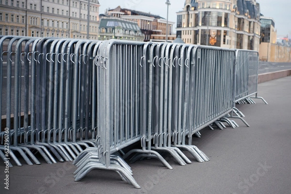 Fototapeta Folded portable temporary fence parts on sidewalk. Preparation for roads and sidewalk closing in case of possible protests or mass events and a large crowd of people.
