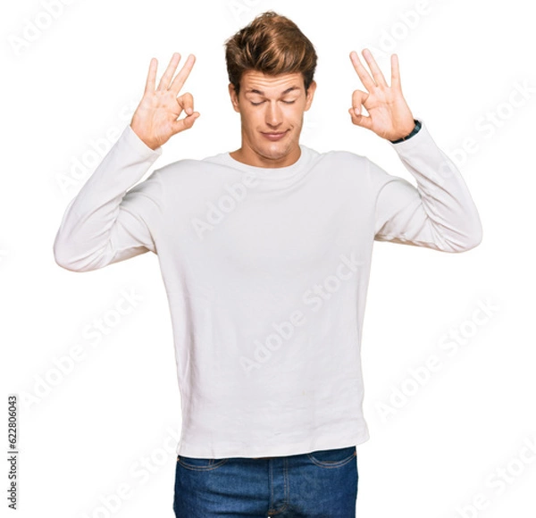 Obraz Handsome caucasian man wearing casual white sweater relaxed and smiling with eyes closed doing meditation gesture with fingers. yoga concept.