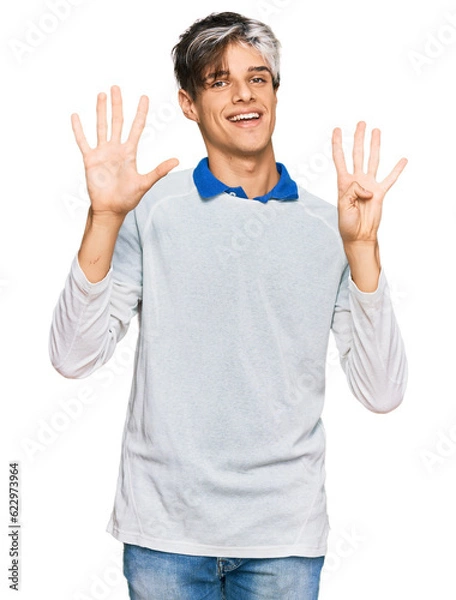 Fototapeta Young hispanic man wearing casual clothes showing and pointing up with fingers number nine while smiling confident and happy.