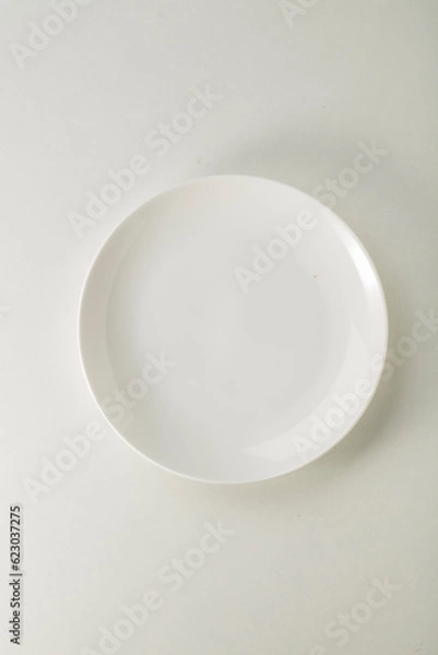 Fototapeta Plato blanco vacío  sobre fondo blanco. Vista cenital. Empty white plate on white background. overhead view.