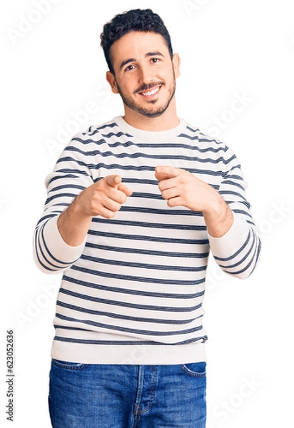 Fototapeta Young hispanic man wearing casual clothes pointing fingers to camera with happy and funny face. good energy and vibes.