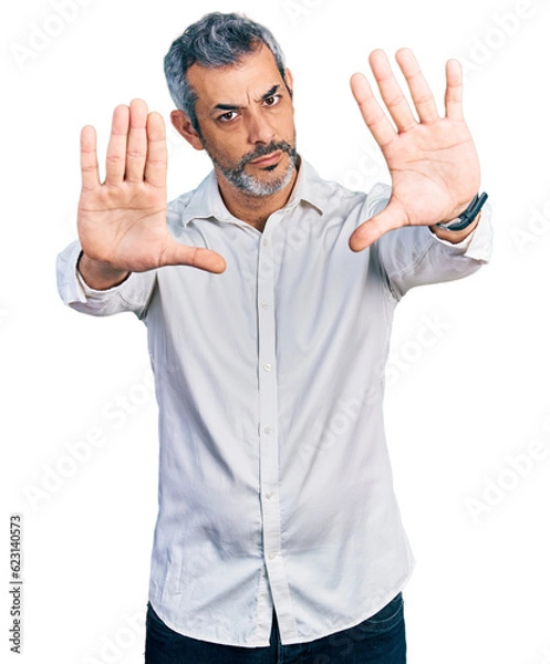 Obraz Middle age hispanic with grey hair wearing casual white shirt doing frame using hands palms and fingers, camera perspective