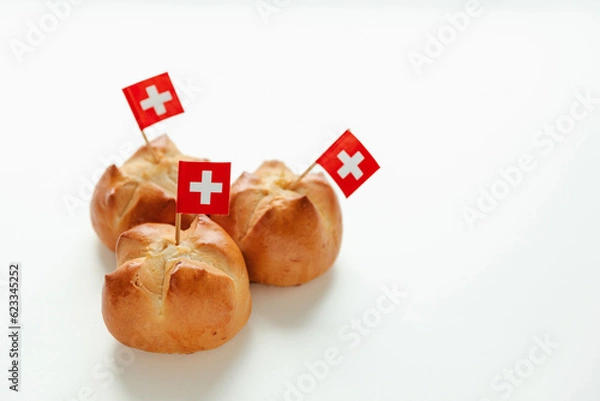 Fototapeta Traditional Swiss bread bun with a cut in the shape of the Swiss flag called in German Augustweggli being baked on the eve of the Swiss National Day on August 1st