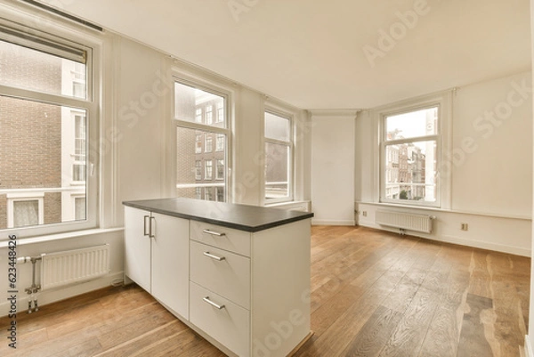Fototapeta an empty kitchen with wood flooring and white cabinets in the room is very spacious, but it's not too