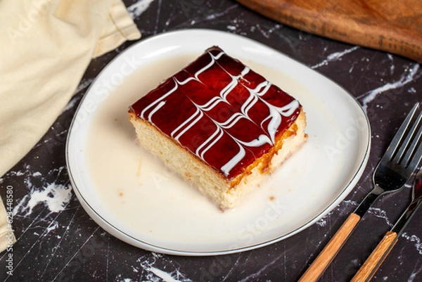 Fototapeta Trilece dessert with milk and caramel. Slice of caramel cake on dark background