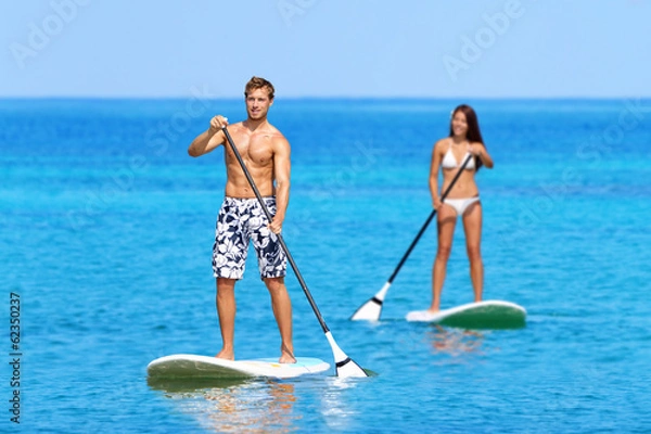 Fototapeta Ludzie na plaży na desce do wiosłowania na stojąco