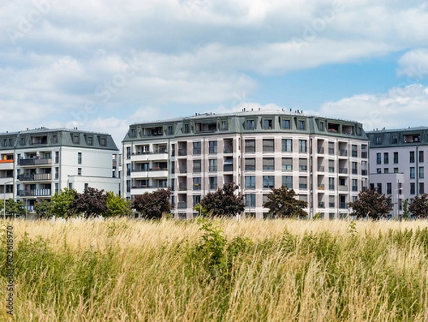 Fototapeta Modern residential buildings in the Dresden Mickten district. Facades with balconies are part of the architecture. The property is an investment. A meadow is in the foreground.