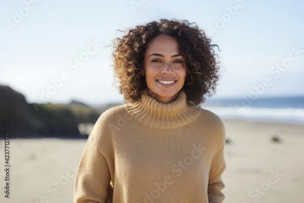 Fototapeta Portrait of smiling young woman standing on beach on an autumns day