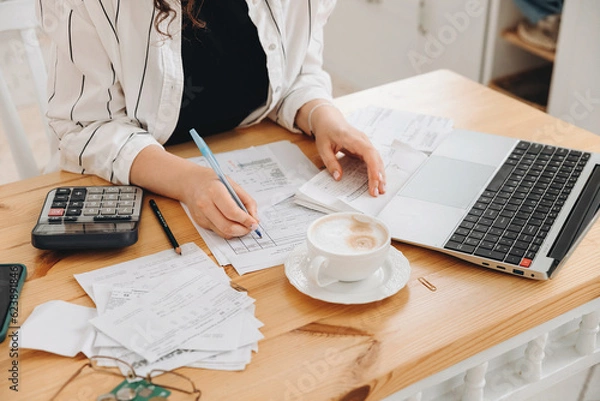 Obraz Close-up hands of unrecognizable woman work at home in the kitchen with financial papers, counting on a calculator, paying bills, planning a budget to find a way to save money. Independent accounting