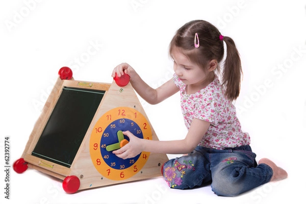 Fototapeta Girl studying while on toy hours sitting on the floor, on white