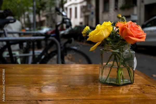 Fototapeta a vase with roses on a table of a cafe, usable as background