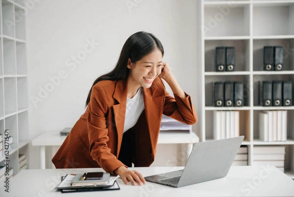 Fototapeta Asian business woman are delighted and happy with the work they do on their tablet, laptop and taking notes at the office..