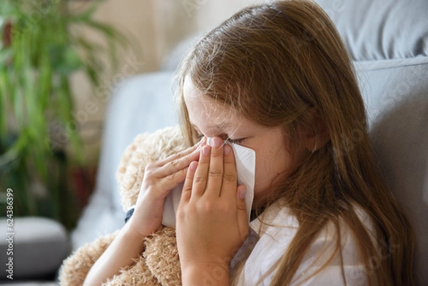 Obraz the girl sits hugging a soft toy and sneezes. Allergy to house dust mites