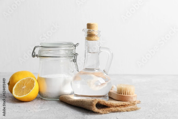 Fototapeta Jug of vinegar, baking soda, brush, napkin and lemons on table
