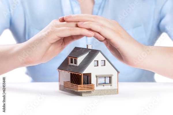 Fototapeta Insurance and house protection concept. House under womans hand
