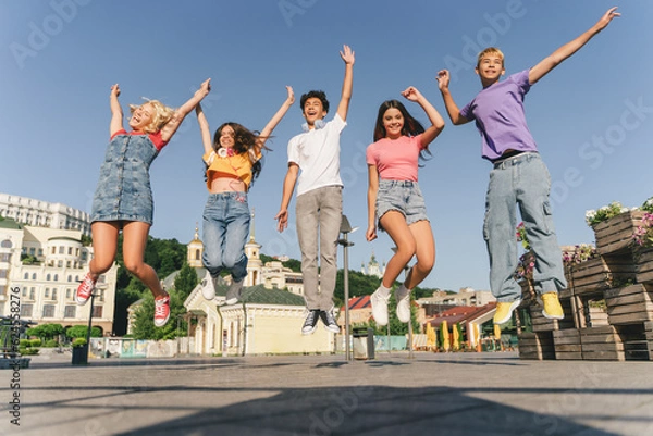 Fototapeta Group of multiracial overjoyed friends, happy teenagers jumping high, having fun, Happy girl and boys celebration summer holidays on the street. Friendship, positive lifestyle, summer concept 