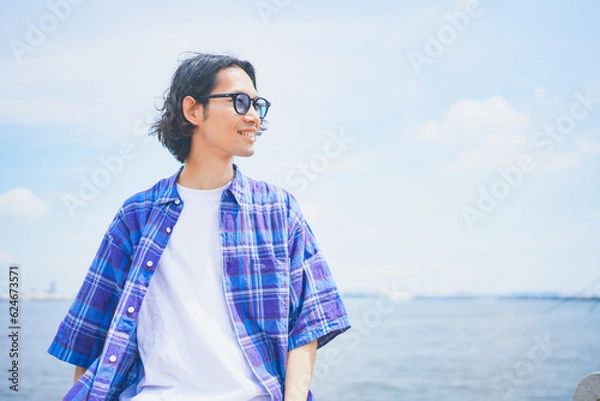 Fototapeta 夏空の下で海風を感じる男性のポートレート