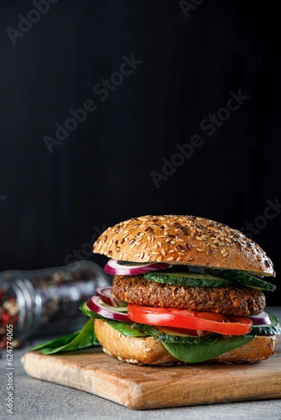 Fototapeta Veggie burger with with onion, cucumber and tomato on a black plate and black background