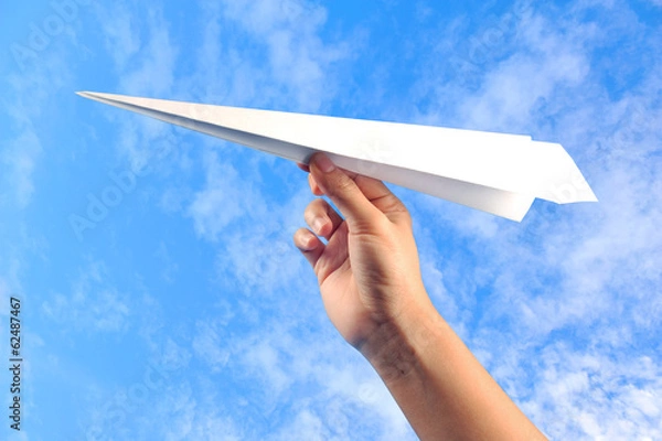 Fototapeta hand with paper plane against blue sky