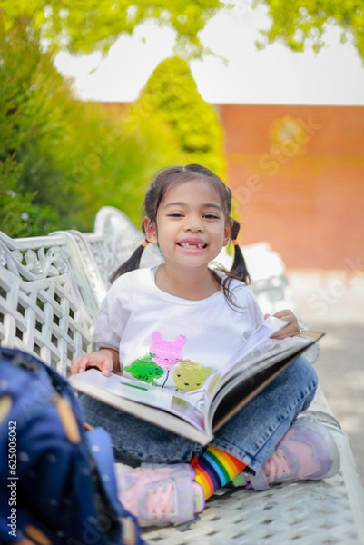 Fototapeta Little kid girl asian reading a book after classes learning homework with intention which increases the development and enhances the classroom learning skills. Concept Back to school.