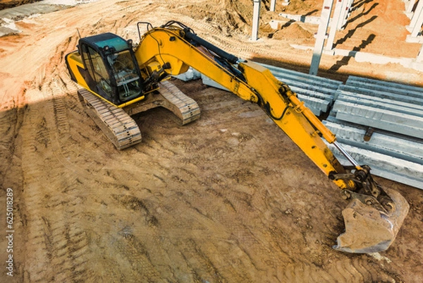 Fototapeta A powerful crawler excavator is working on a construction site. Close-up. View from above. Preparation of a pit for construction. Excavation.