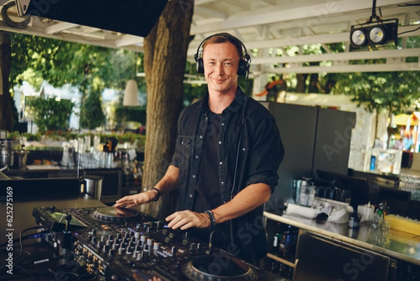 Fototapeta DJ at the mixing console on the summer playground smiling looking at the camera