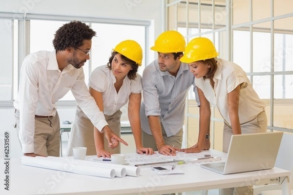 Fototapeta Colleagues working on blueprints at office