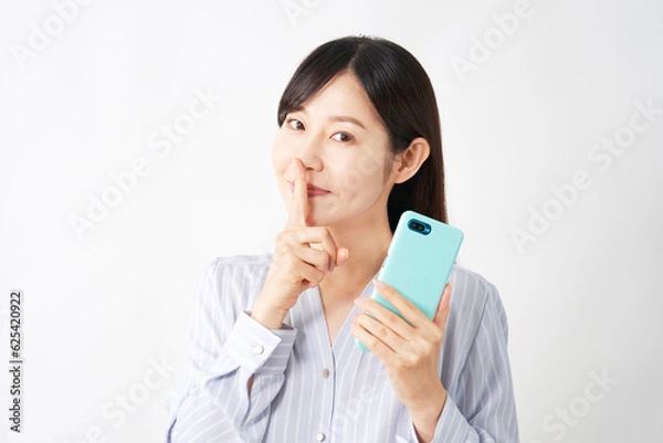 Fototapeta スマートフォンを持って内緒のポーズをするミドルエイジの女性　白背景