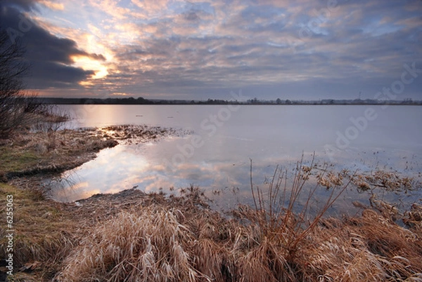 Fototapeta Ice melting on a lake at sunset
