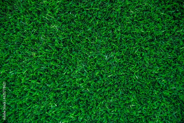 Fototapeta The texture of green artificial grass.Covering for sports stadiums and decorations.