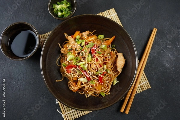 Fototapeta Stir fry noodles with vegetables and chicken meat in a bowl.