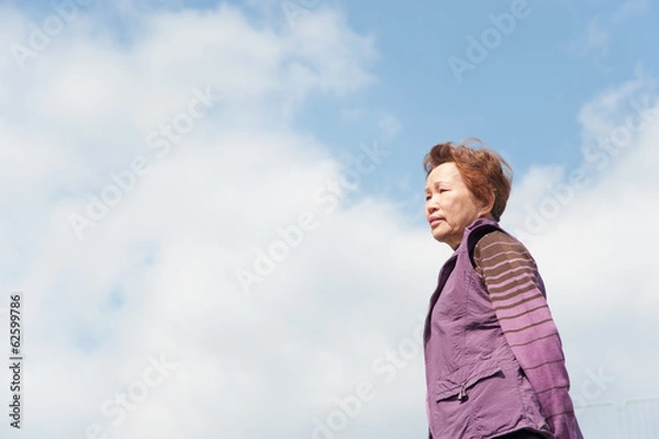 Fototapeta 青空をバックに撮影した高齢者の女性