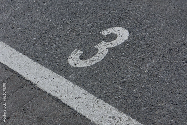 Fototapeta a number 3 painted on asphalt parking spot